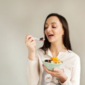 woman-eating-porridge-fruits-using-spoon-young-51209954